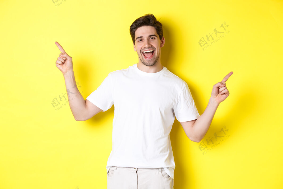 黄色快乐时尚的家伙展示了两个变种 手指指向左右两侧的宣传片 站在黄色背景上自信工作室站