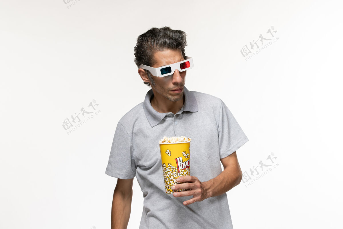 正面正面图年轻男性手持爆米花包 戴着d型太阳镜 白色表面青少年遥控孤独