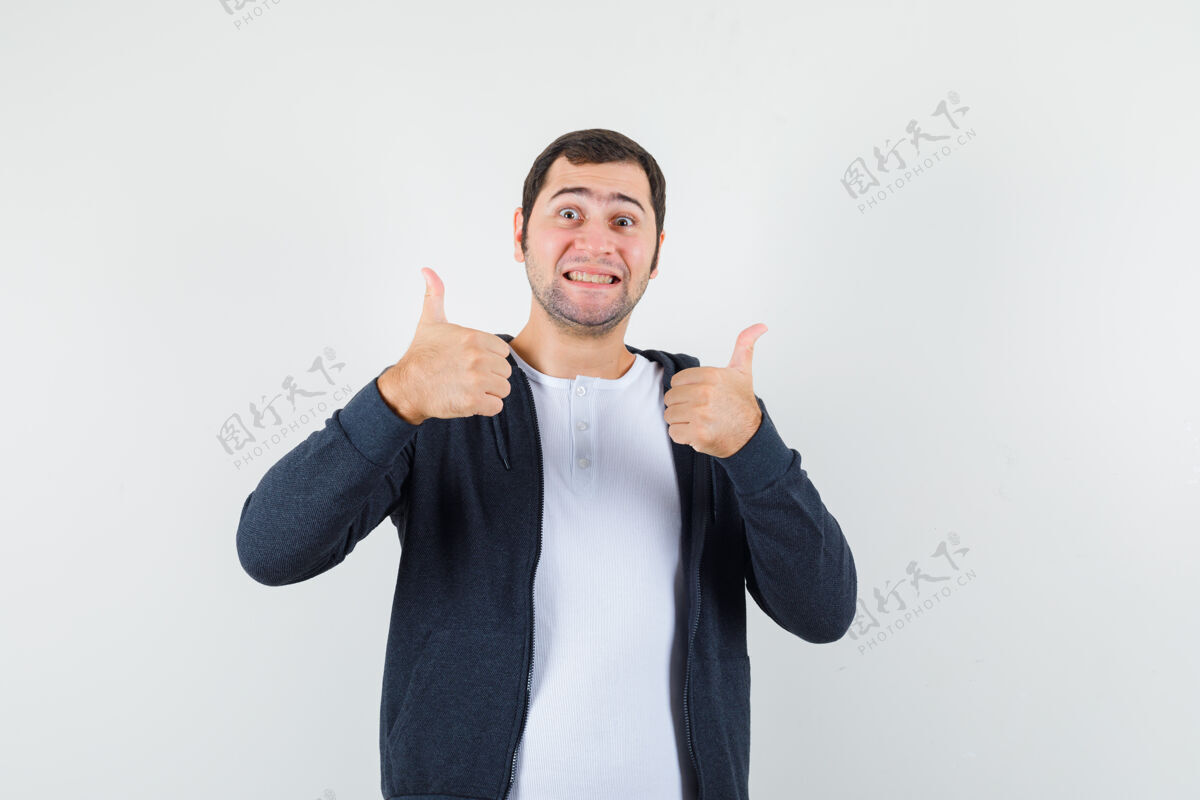 年轻身穿t恤衫 夹克衫的年轻男性 向上竖起大拇指 看上去很快乐 正面视图T恤男人夹克