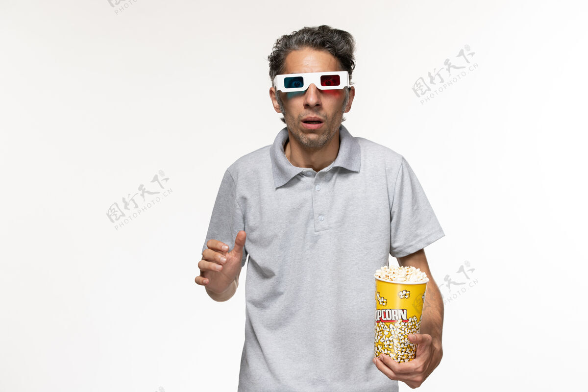 太阳镜正面图：戴着d型太阳镜在白色地板上吃爆米花的年轻男性电影《孤独的遥控器》遥控前面护目镜