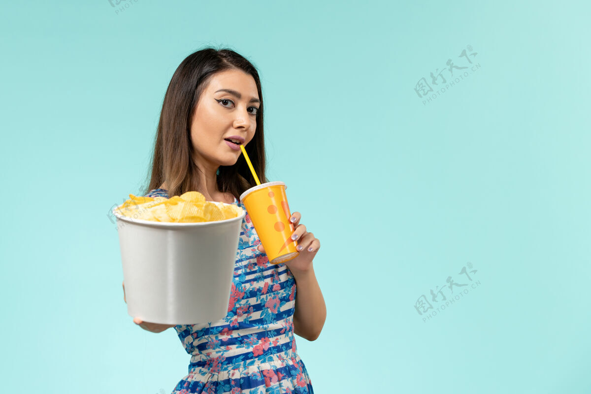 电影正面图年轻的女性拿着篮子和薯片 在蓝色的水面上喝水举行筹码剧院
