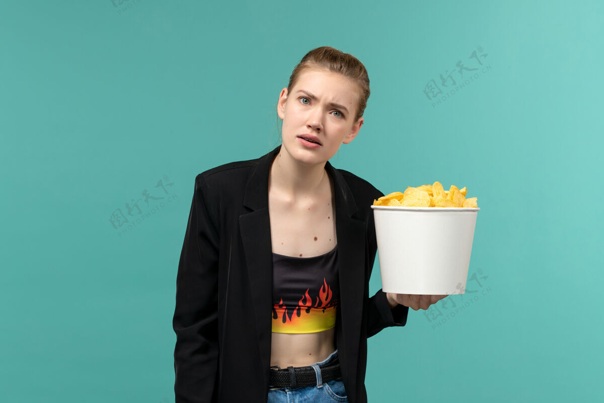 办公桌正面图：年轻女性在蓝色桌子上吃薯片看电影电影年轻女性电影院