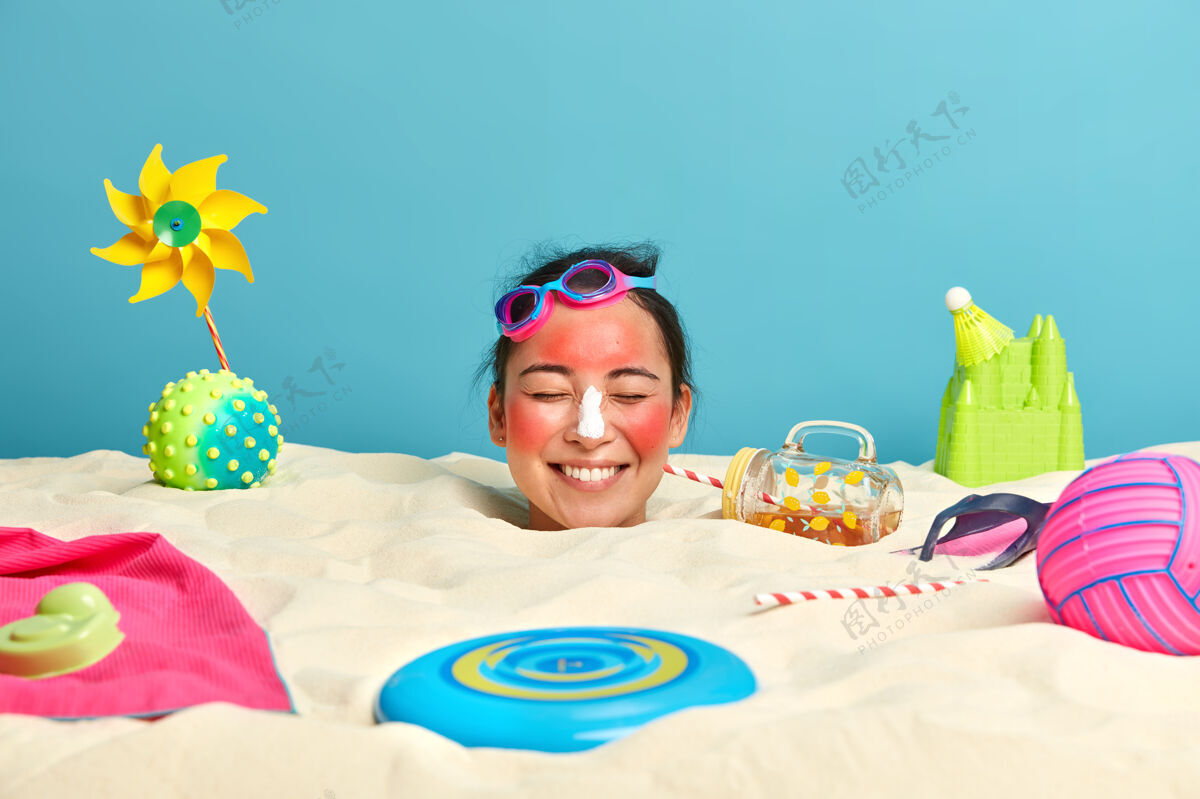 休闲年轻女子头上涂着防晒霜 脸上围着沙滩饰品女人微笑玩具