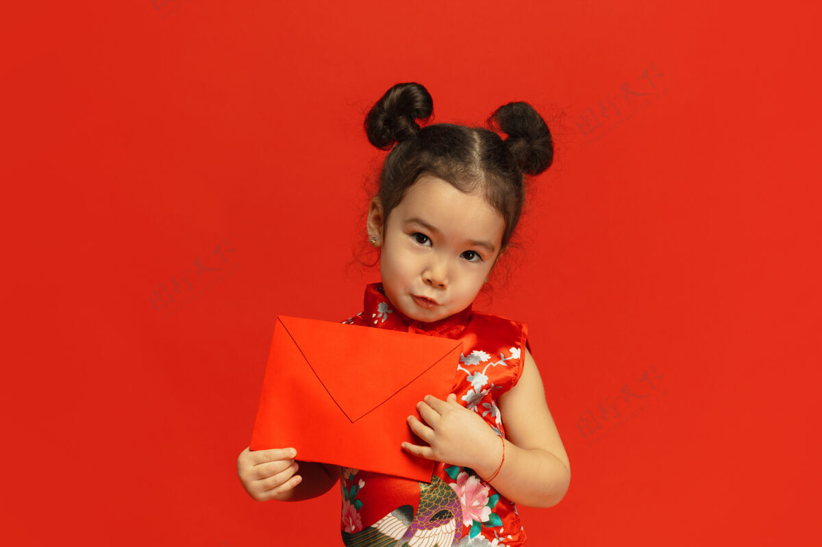 中国新年穿着传统服装的亚洲可爱小女孩被隔离在红墙上年轻人节日文化