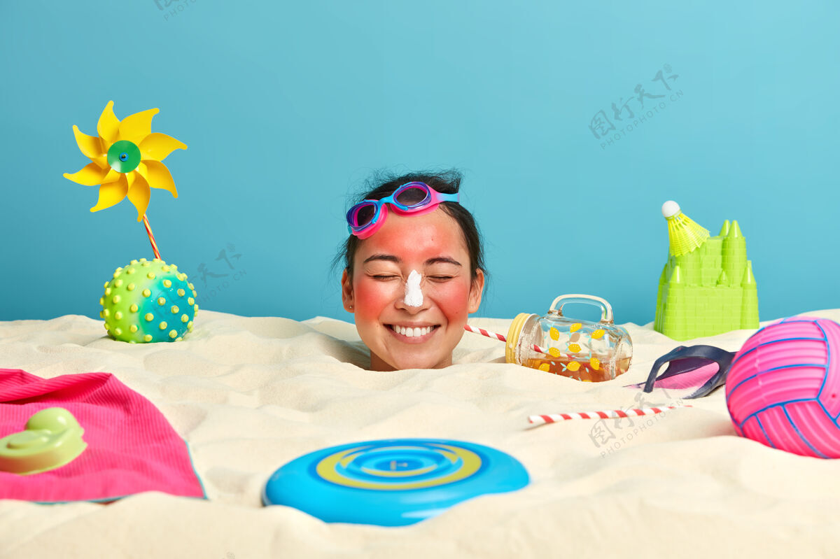 请年轻女子头上涂着防晒霜 脸上围着沙滩饰品日光浴海滩休息