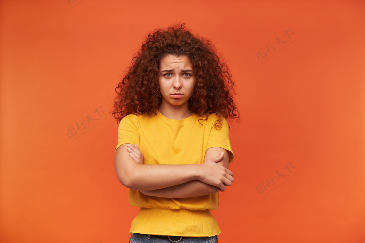 休闲一个愁眉苦脸的女人 卷曲的姜黄色头发 穿着黄色t恤皱眉红发女性