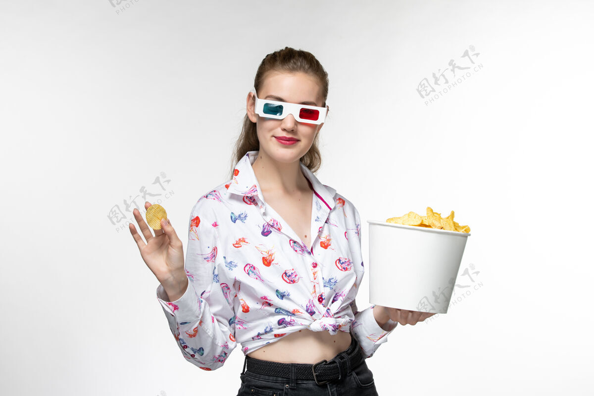 电影正面图：戴着d型太阳镜拿着薯片的年轻女性手提篮 在白色的表面上微笑篮子年轻女性太阳镜