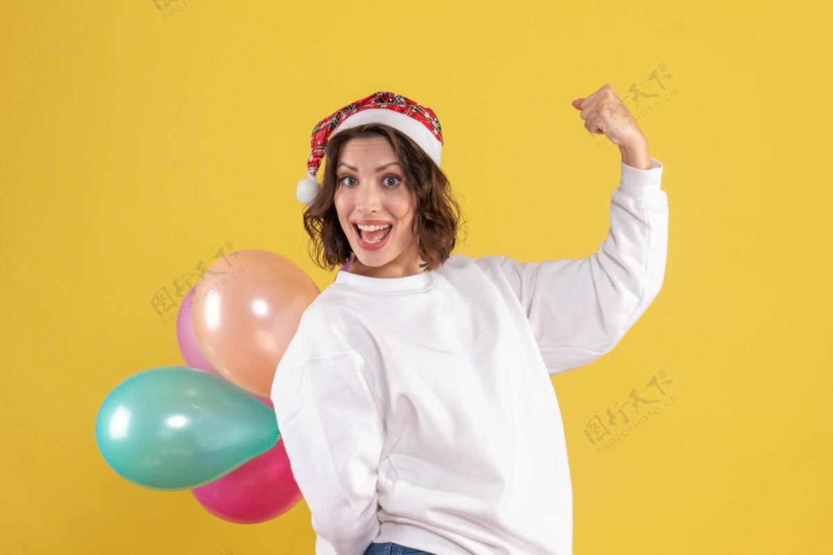 情感正面图年轻女子黄色书桌上藏着五颜六色的气球新年圣诞彩色节日女子感慨正面欢呼健身