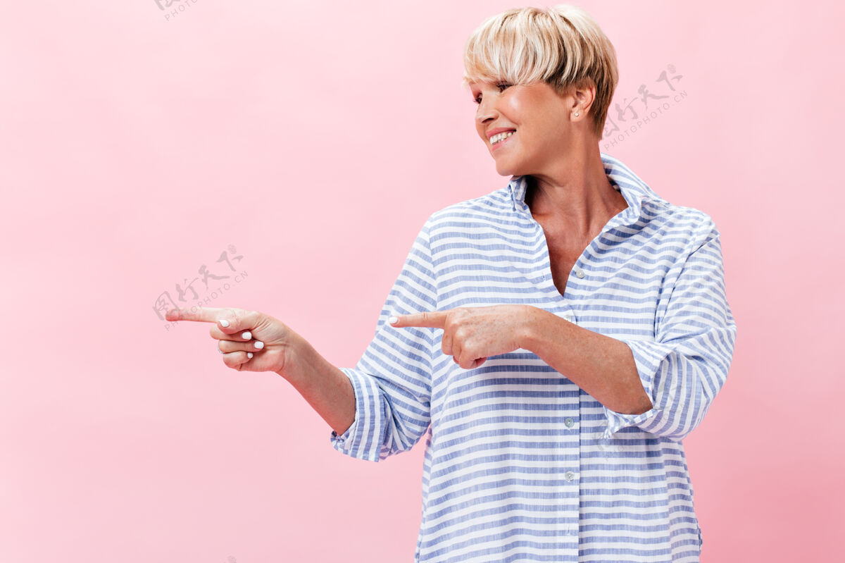 粉色背景穿格子衬衫的成年女子指着地方发短信化妆品年休闲