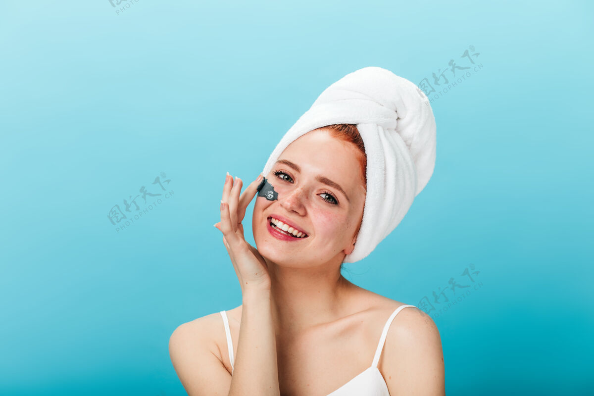 微笑美丽的年轻女子正在敷面膜摄影棚拍摄的灵感女孩在蓝色背景下微笑着做护肤护理皮肤护理治疗人