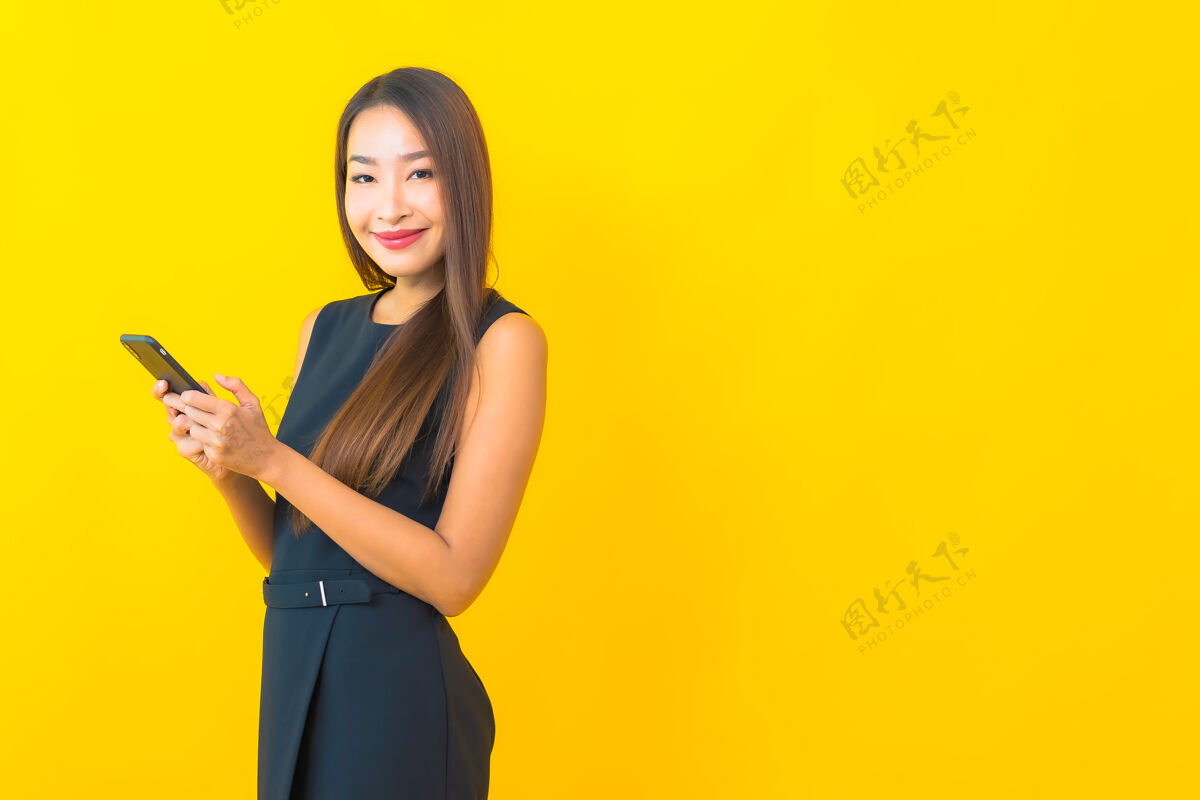 女士一幅美丽的亚洲女商人的画像 黄色背景上有咖啡杯和智能手机电话聪明休闲