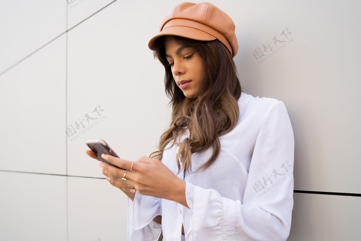 打字站在街上使用手机的年轻女子的肖像城市和通讯概念城市女性在线