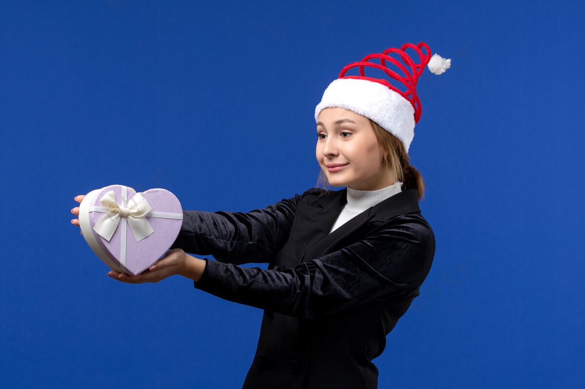 专业正面图年轻女士手持心形礼物在蓝色墙壁新年礼物节日小姐人观点