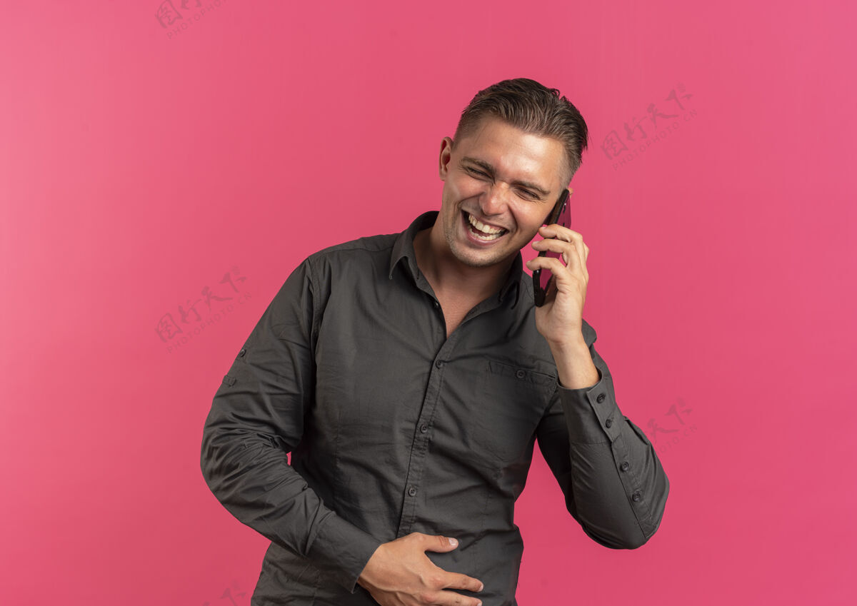 男人年轻快乐的金发帅哥在粉色空间和复印空间上孤立地讲电话年轻电话英俊