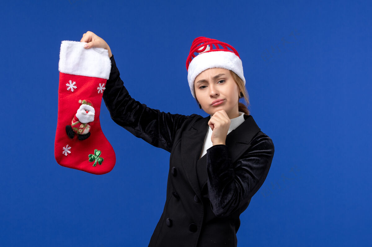 看法正面图：年轻女子拿着圣诞袜站在蓝色的墙上过年妇女过节专业袜子微笑