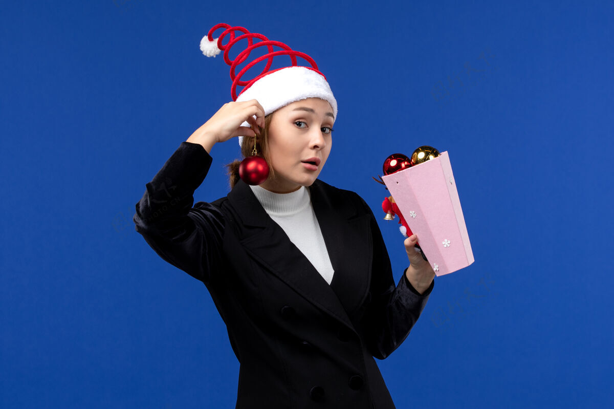 成功正面图：年轻的女性拿着圣诞树玩具在蓝色的书桌上蓝色的情感新年假期办公桌人西装