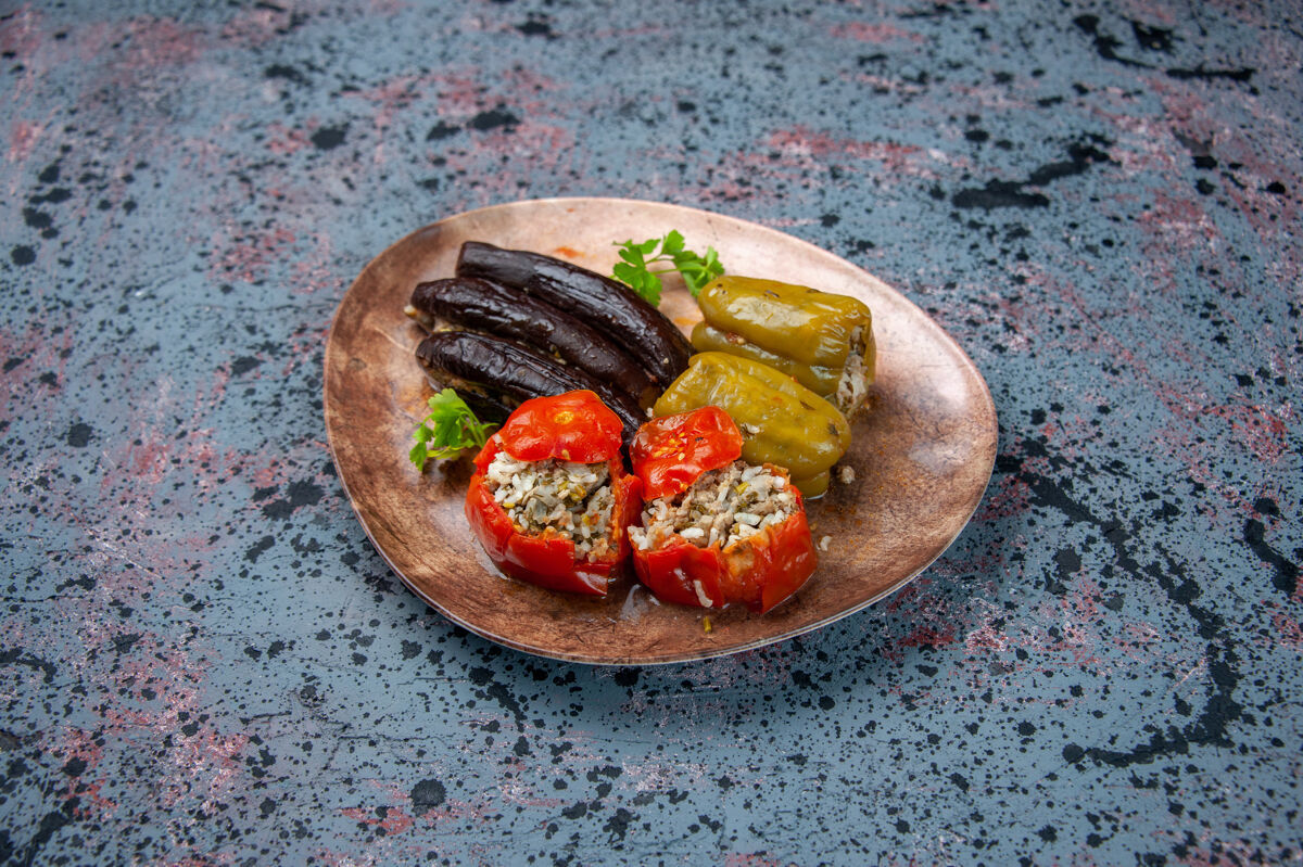 肉前视图茄子与煮熟的西红柿和甜椒与肉末填充在蓝色背景板内多尔玛前面地面菜肴
