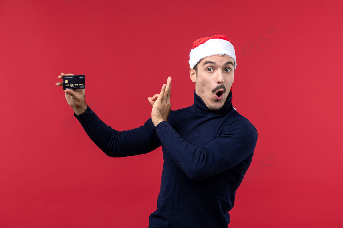 男人正面图年轻男子手持红色背景的黑色银行卡银行红色圣诞