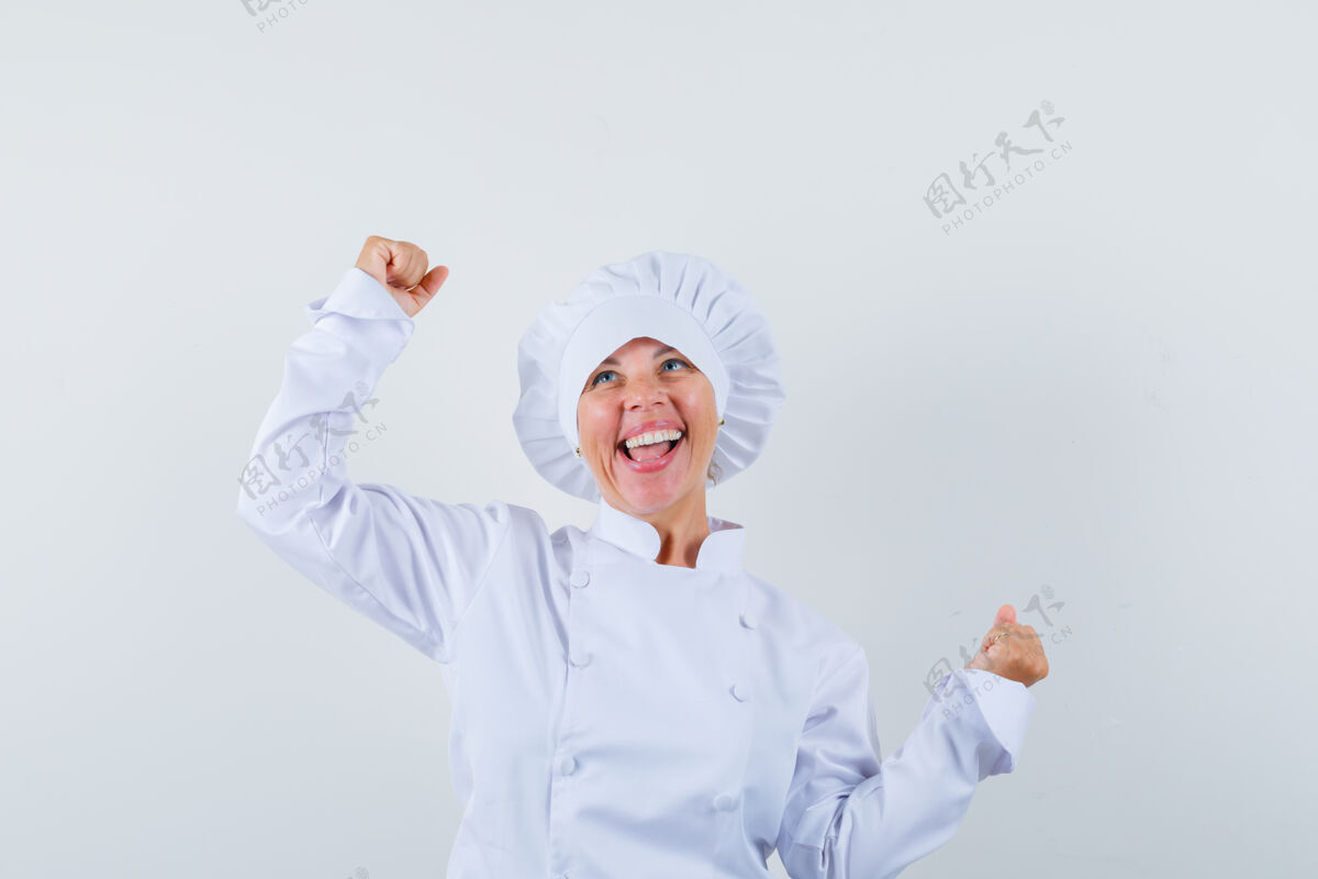 魅力身着白色制服的女厨师展示着赢家的姿态 看上去很幸福厨师显示喜悦