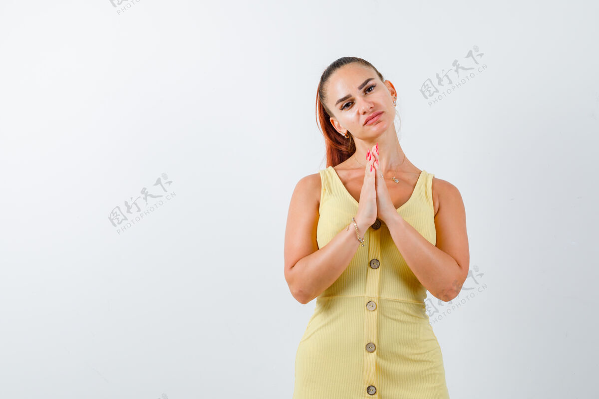 信心身穿黄色连衣裙的年轻女士手牵手祈祷 看上去充满希望正面图户外命运前进