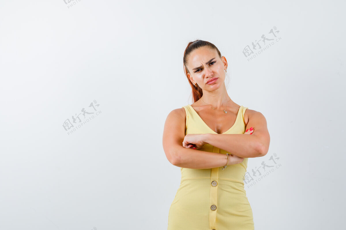 折叠年轻的女士抱着双臂 穿着黄色的裙子 看起来很失望 前面的景色手臂不高兴女人