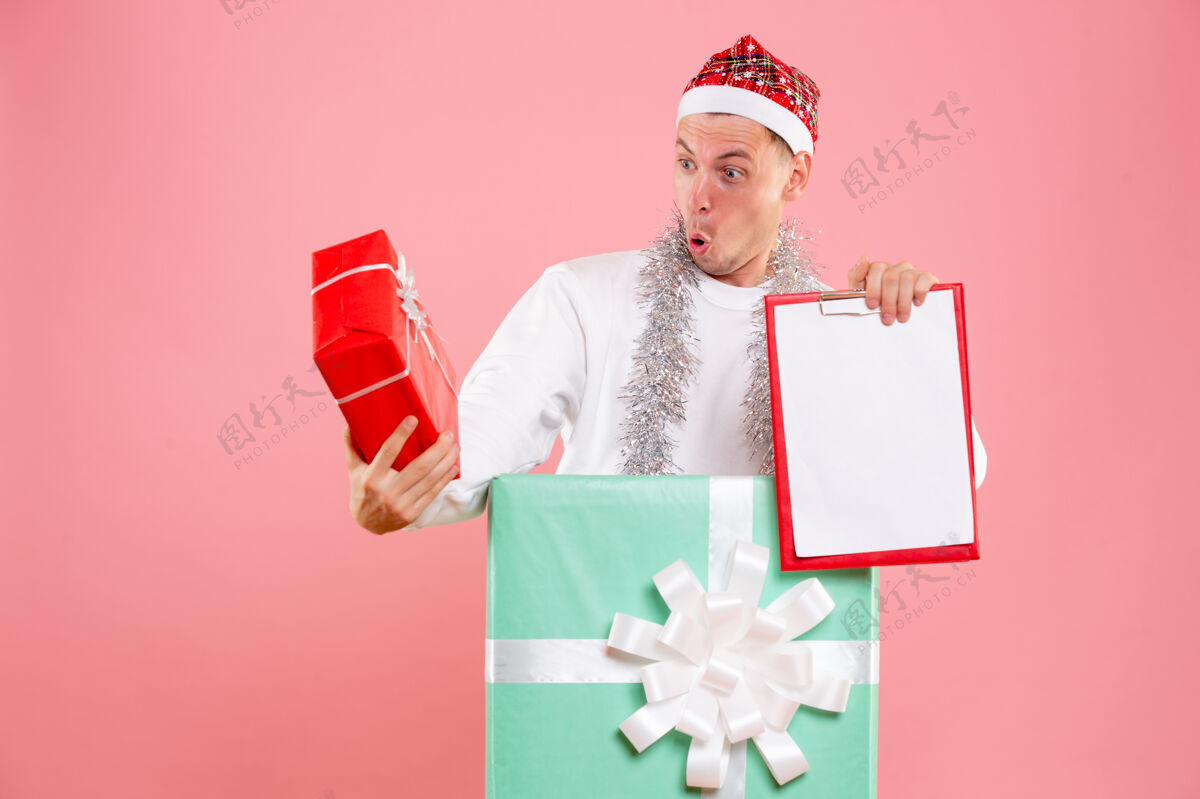 粉色正面图年轻的男性在目前持有文件 目前在粉红色的背景视图前面礼物