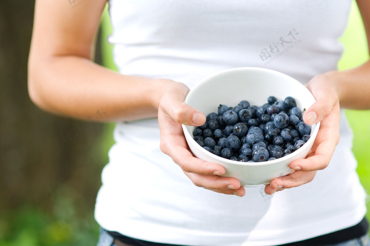 新鲜拿着满满一碗蓝莓的女人收获健康生活方式户外
