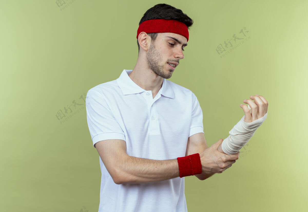 触摸戴着头巾的年轻运动型男子抚摸着缠着绷带的手腕 感到绿色的疼痛感觉绷带运动