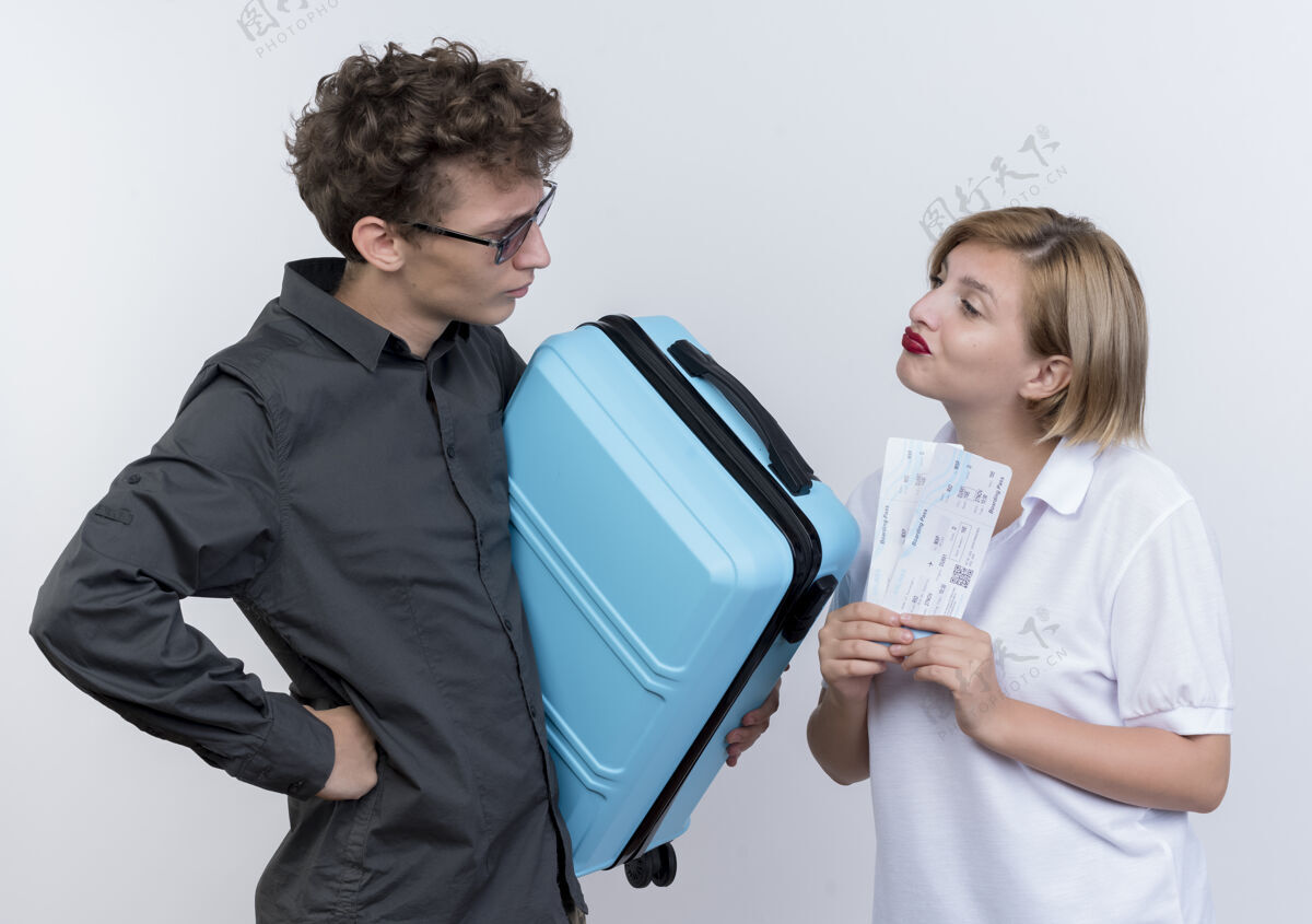 手提箱一对快乐的年轻游客男子拿着手提箱看着他自信的女友手里拿着机票翻白脸男人机票女朋友