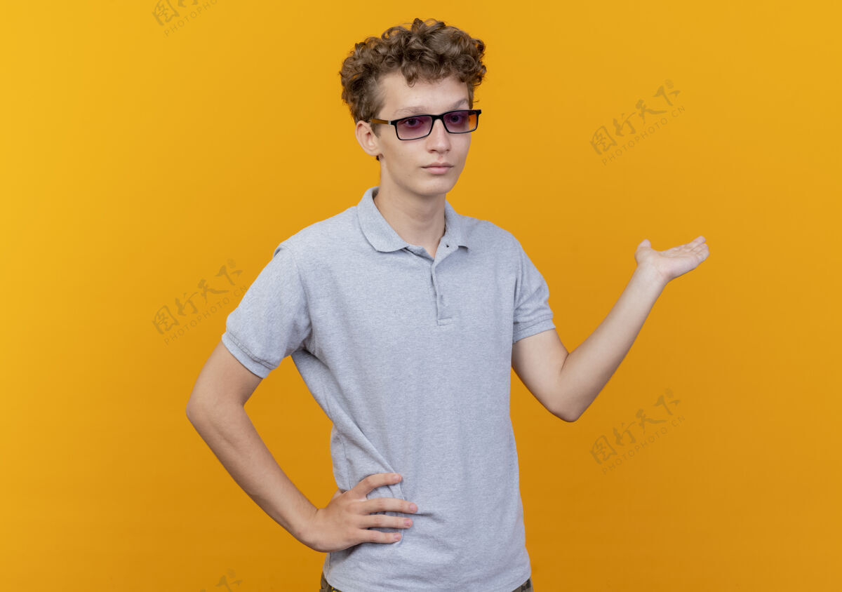 橙色戴着黑眼镜的年轻人穿着灰色马球衫 手举着什么东西 看起来比橙色更自信手臂穿介绍