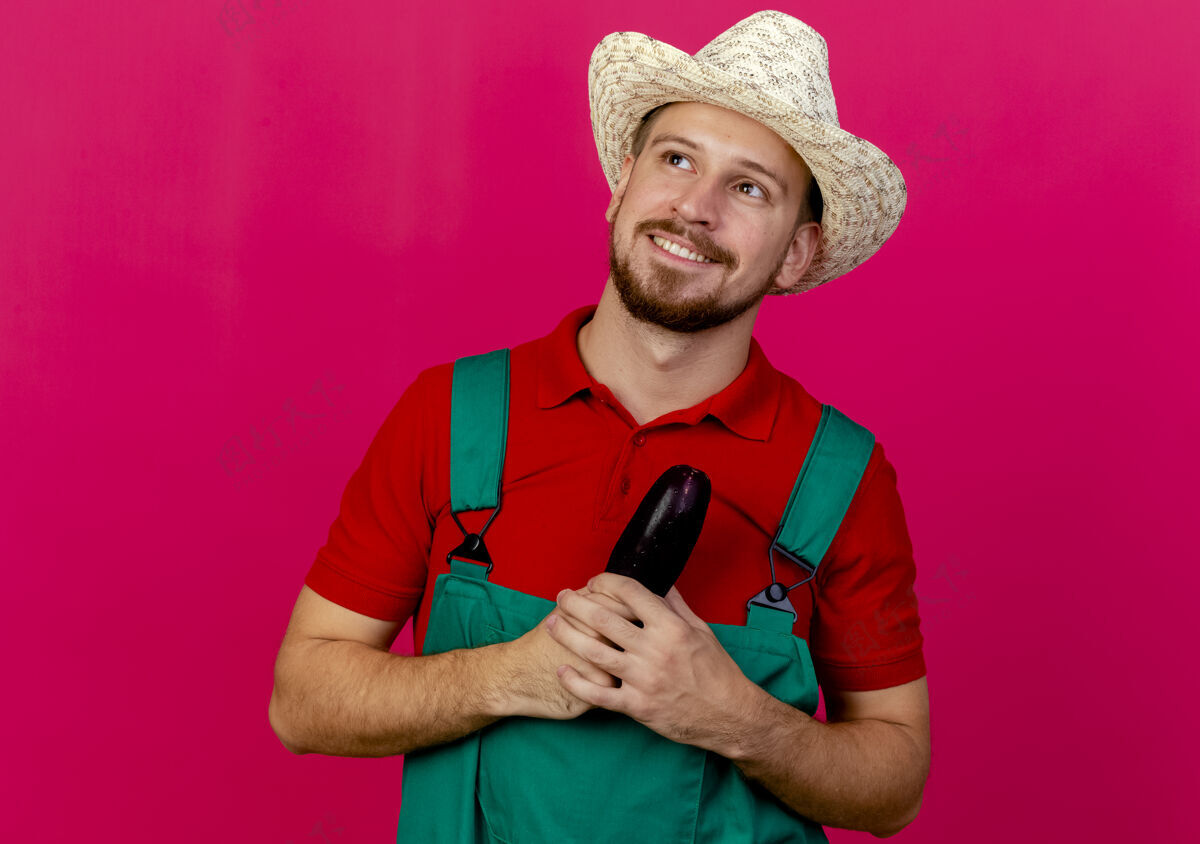 茄子面带微笑的年轻英俊的斯拉夫园丁 身着制服 戴着紫红色的帽子望着一旁人年轻微笑