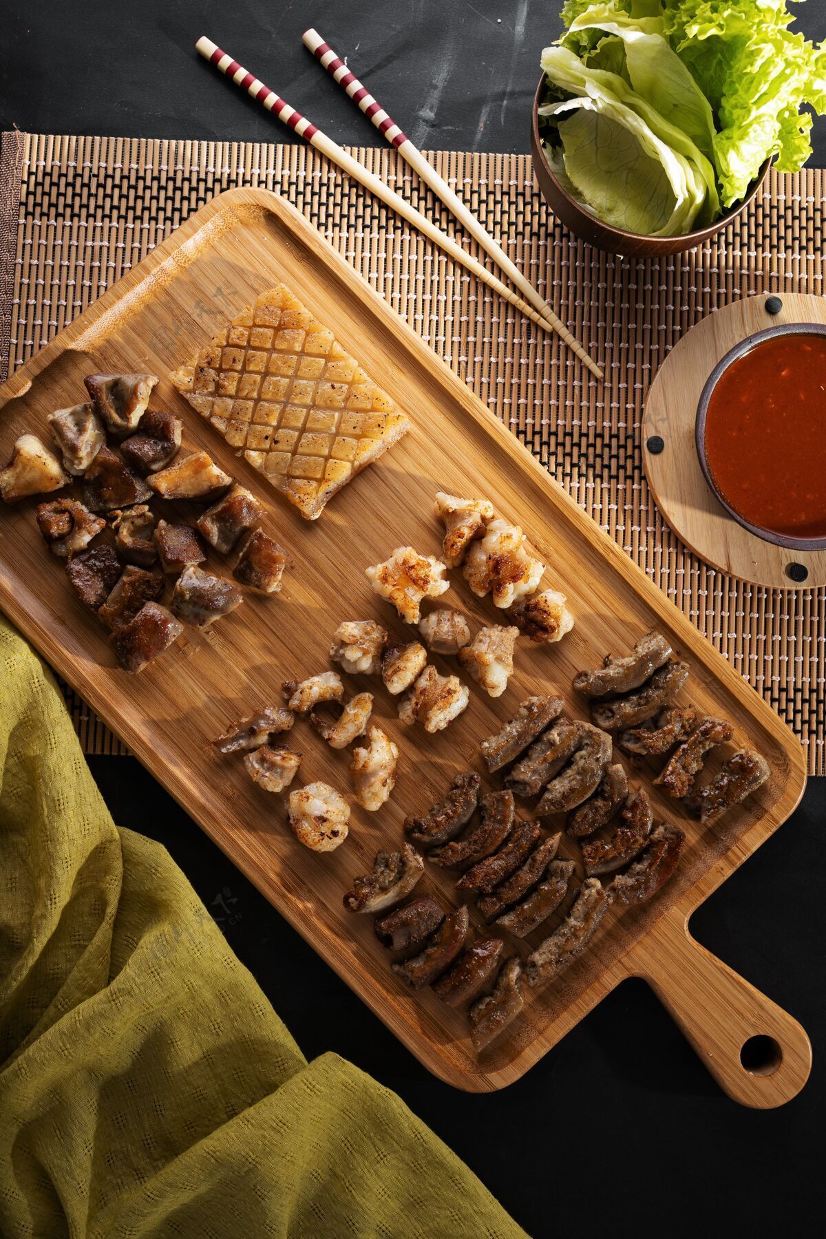 筷子垂直高角度拍摄的黑色表面上装满烤食品的木盘香料辣柠檬