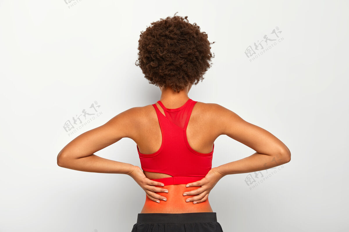 皮肤活跃的运动型女性在运动或跑步后背部受伤 感觉下背部疼痛 头发卷曲 穿着红色上衣和裤子运动员受伤理发
