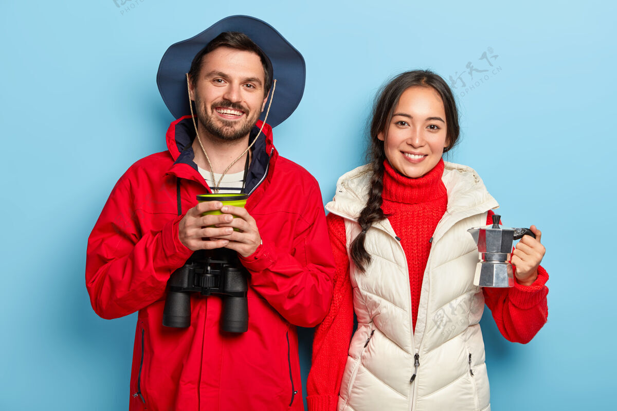 韩国这对幸福的夫妇在大自然中度过周末 喝咖啡 享受新鲜空气 用望远镜 穿着暖和的休闲服 站在蓝色的墙上 彼此挨着旅游咖啡自然