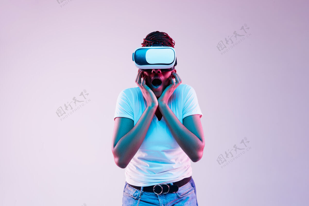 游戏年轻的非洲裔美国妇女在霓虹灯下玩vr眼镜的肖像虚拟现实小玩意美