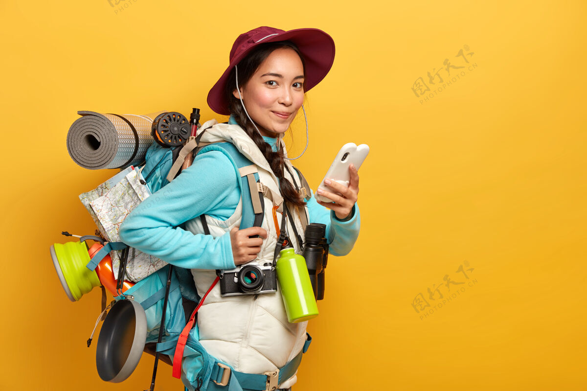 旅程相当满意的旅行者使用智能手机上的免费互联网连接在流浪旅行期间写博客 携带大而重的背包自然微笑数据