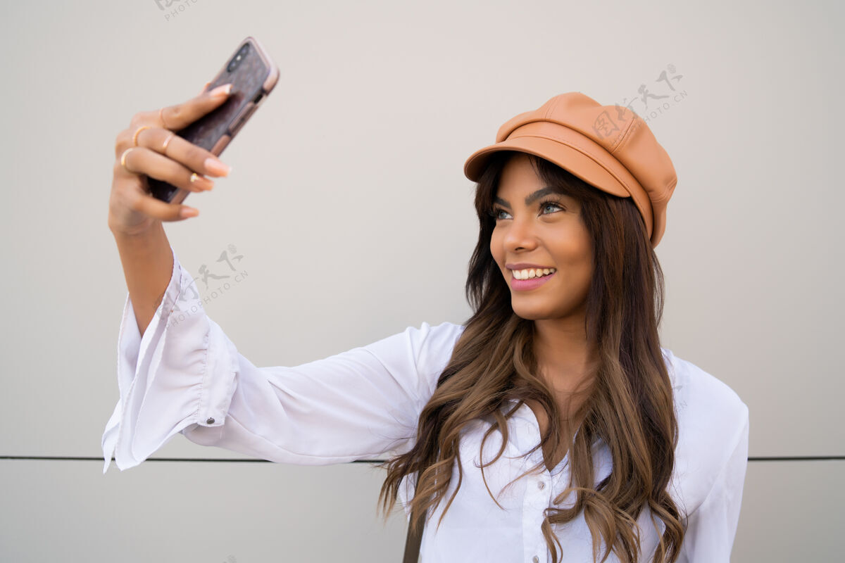 现代年轻女子站在户外用手机自拍的照片摄影师人姿势