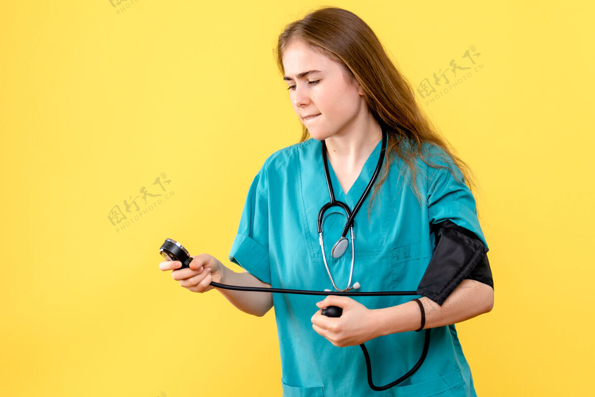 女医生前视图女医生正在测量浅黄色背景上的压力卫生院医护人员制服听诊器护士