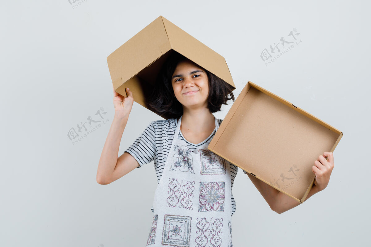 T恤小女孩拿着空纸板箱 穿着t恤 围裙 看上去很高兴 空虚头发发型