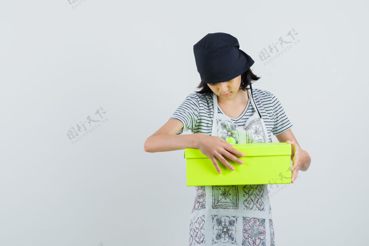女性小女孩穿着厨房的衣服看着礼物盒 好奇地看着 头发积极发型