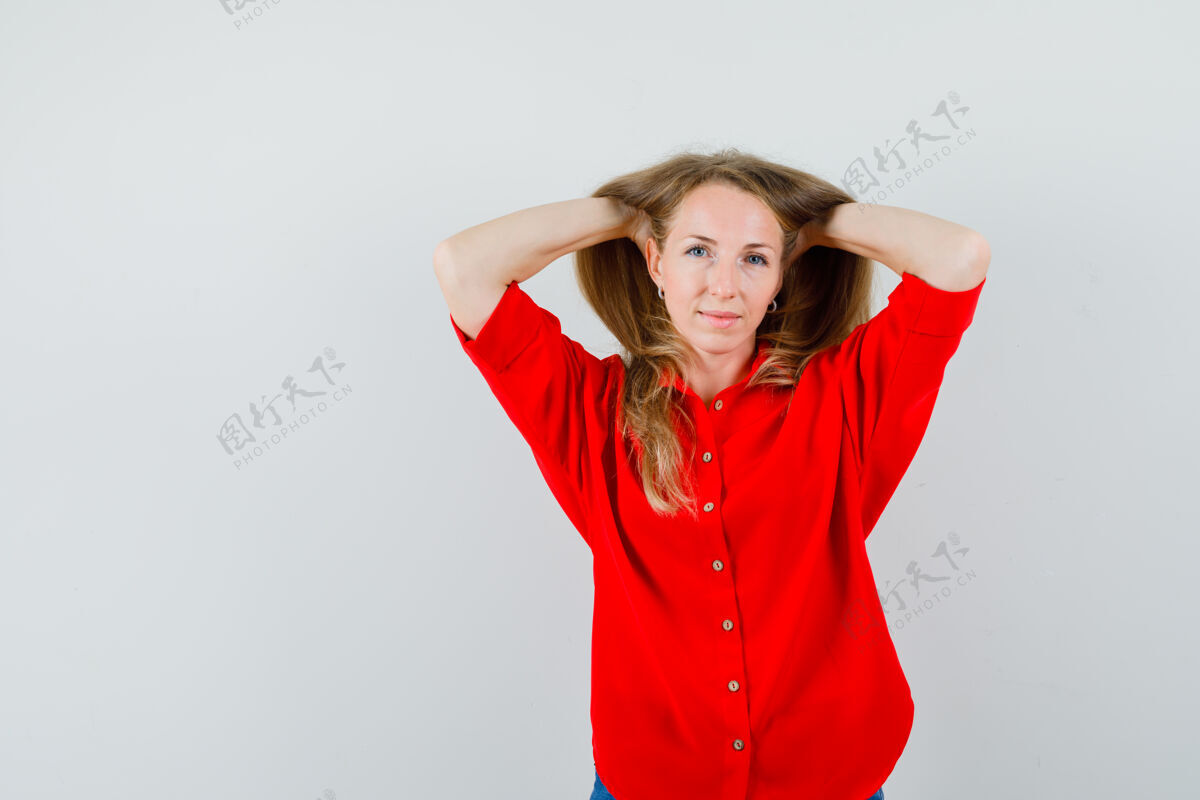 手一个金发女人穿着红衬衫 双手抱着头摆姿势 看起来很迷人 扣姿势华丽