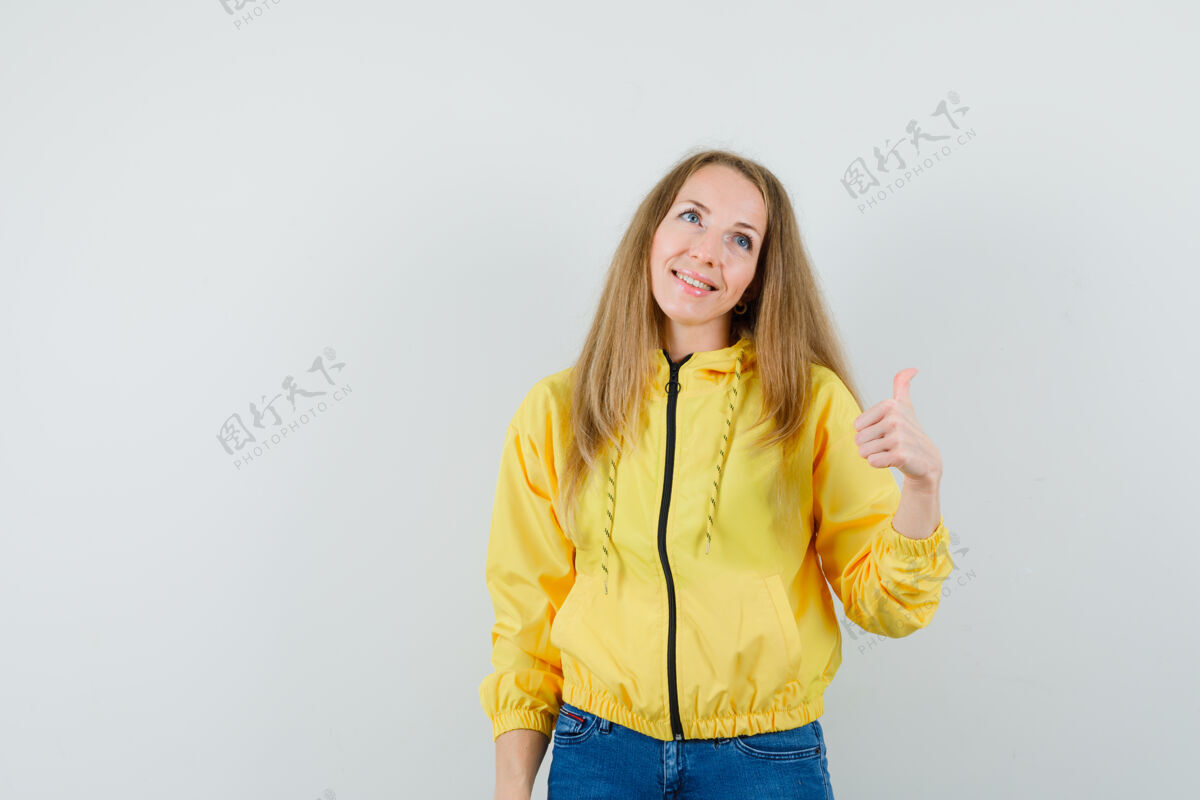 夹克穿着夹克的金发女郎 牛仔裤露出大拇指 看起来很欢快 牛仔裤女性性感