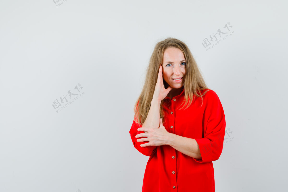 欢快金发女人穿着红衬衫站在思考的姿势 看起来很高兴 健康皮肤思考