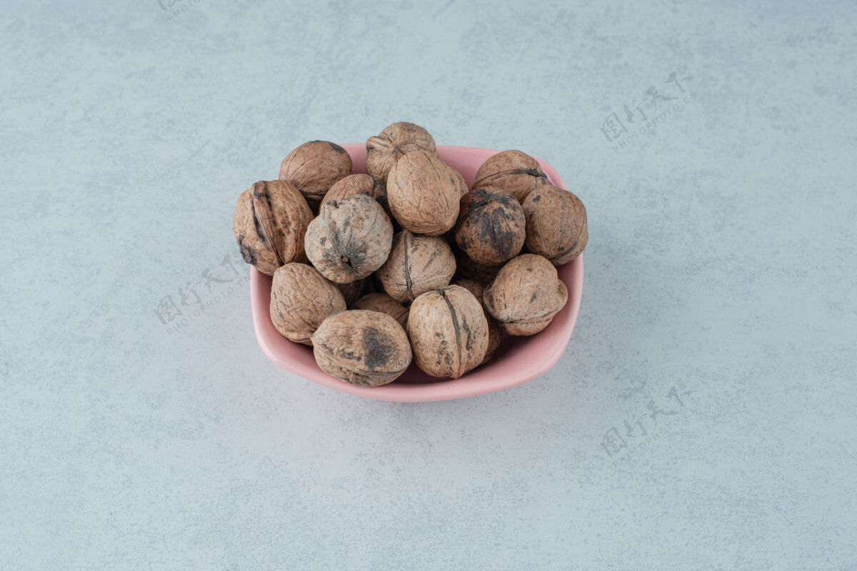 可食用在大理石背景上放满坚果的粉红色小盘高质量照片盘子吃可口