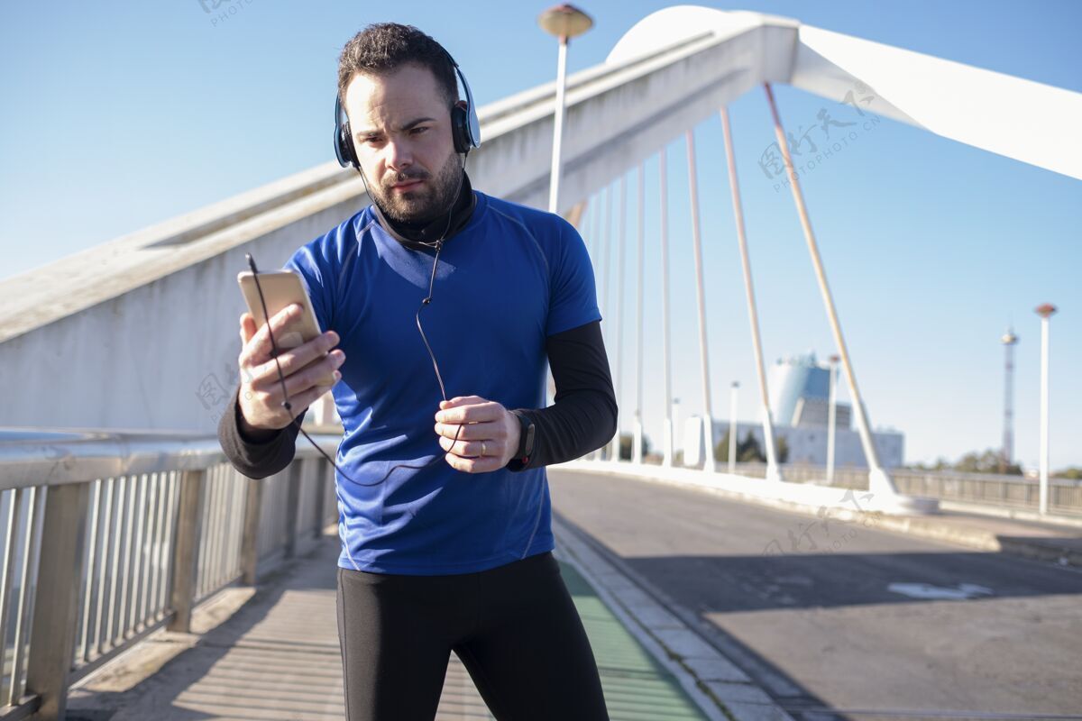 人特写镜头中一个戴着蓝色耳机的男人在街上慢跑时用手机街道户外运动