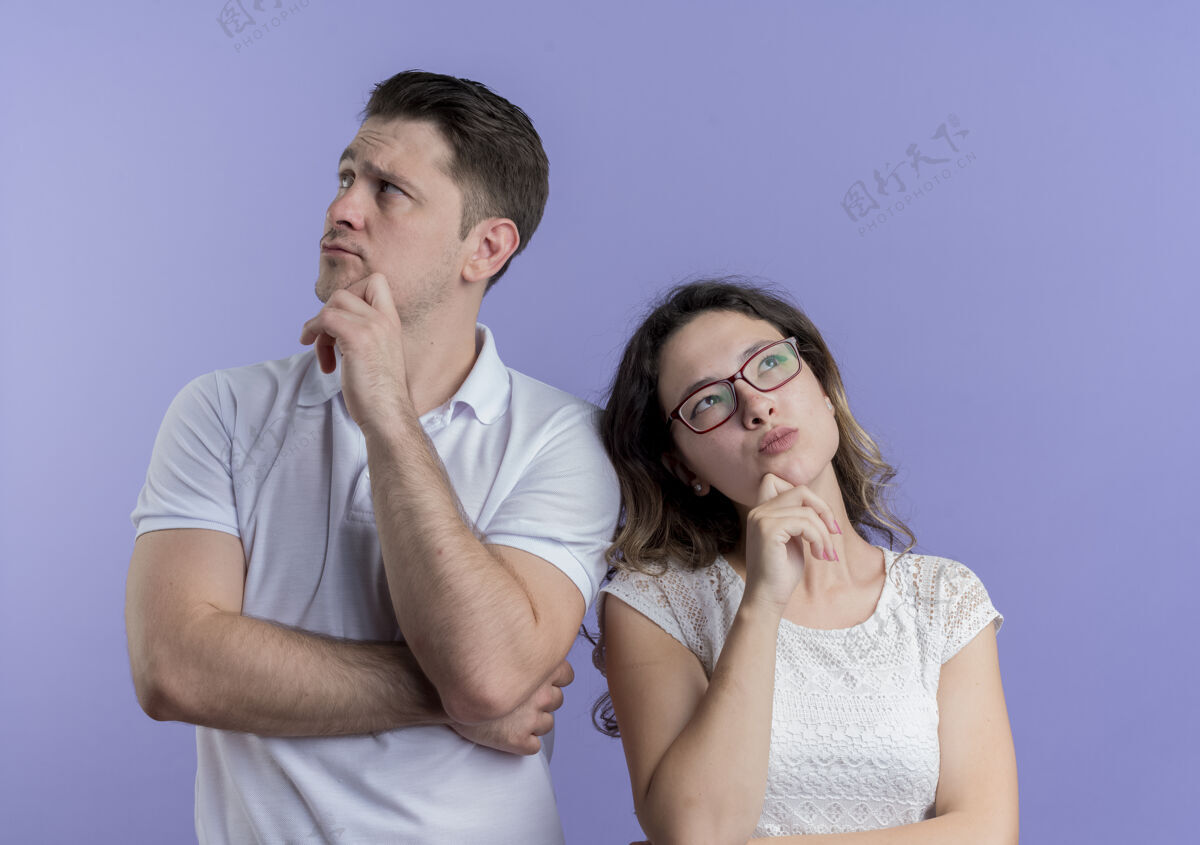 年轻人一对年轻的夫妇站在蓝色的墙上 脸上带着沉思的表情 两眼望去在一旁沉思表情