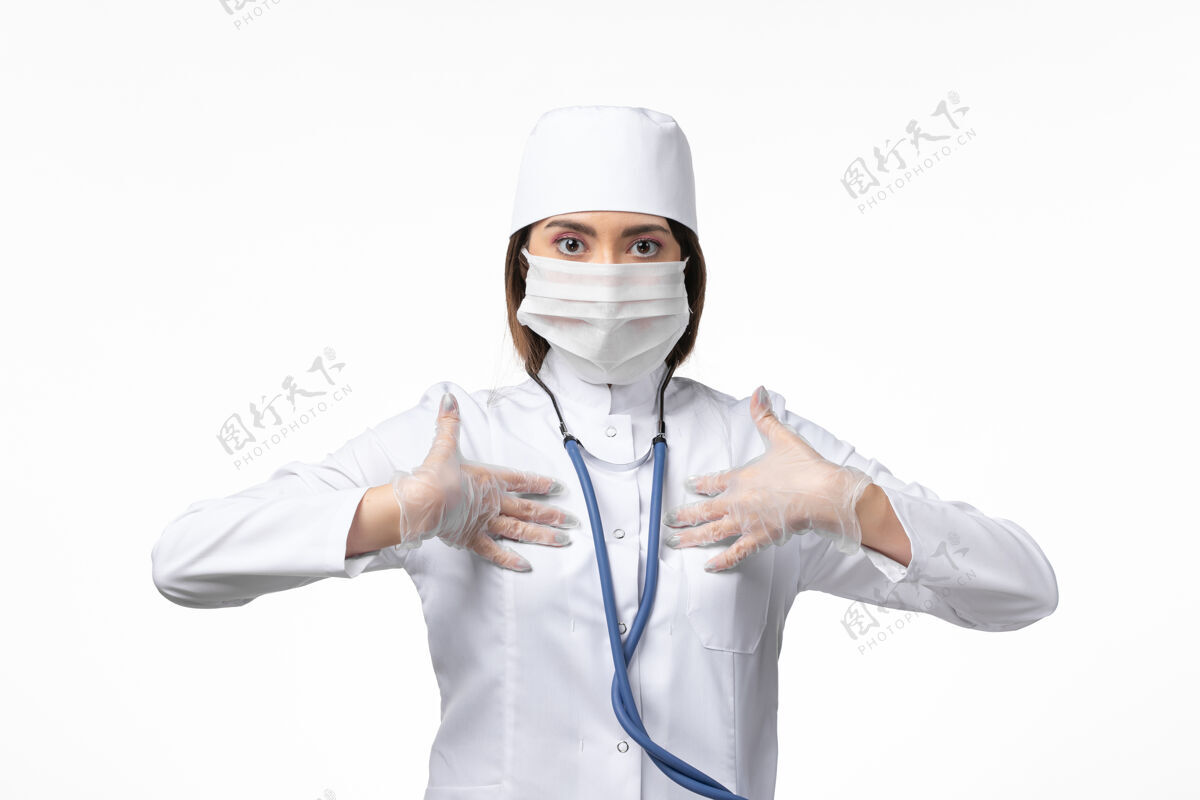 实验室外套前视图：女医生穿着白色医疗服 戴着口罩 由于白墙上出现了大流行性流感病毒covid-医疗正面专业