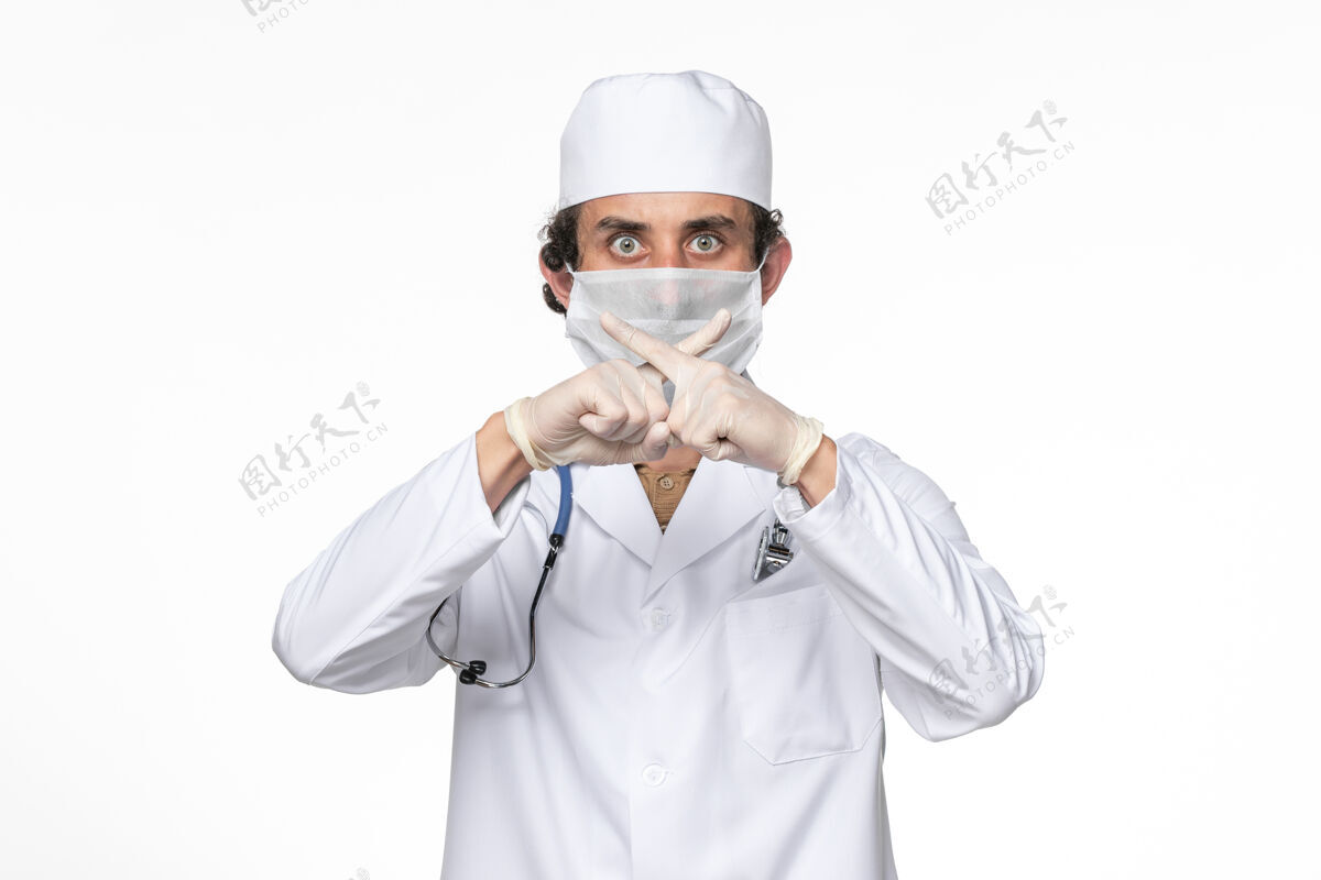 视图正面图：男医生穿着医疗服 戴着口罩 以防白色桌面病毒溅起冠状病毒大流行人冠状病毒人