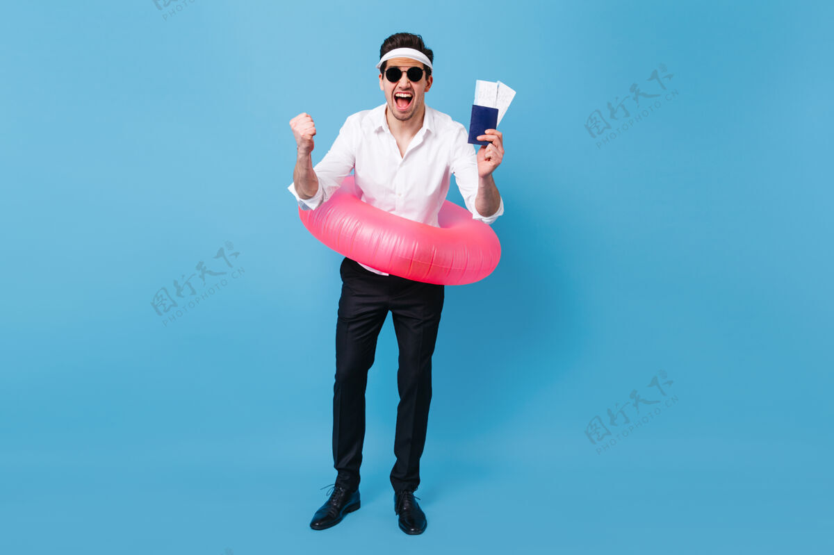 优雅一个穿着西装 戴着太阳镜 手里拿着文件 机票和粉色充气圈的男人享受假期旅行的全长片老板帽子黑发