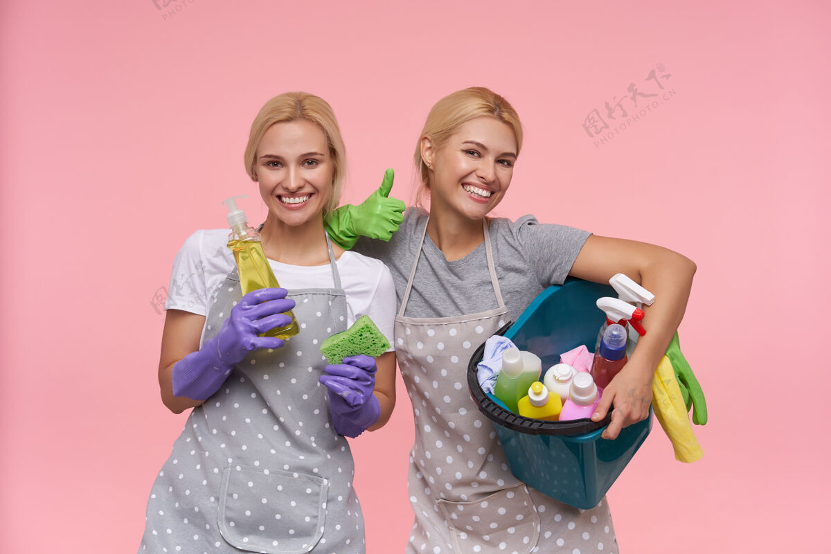 工作年轻的金发可爱的主妇们戴着橡胶手套准备春季大扫除女性化学快乐